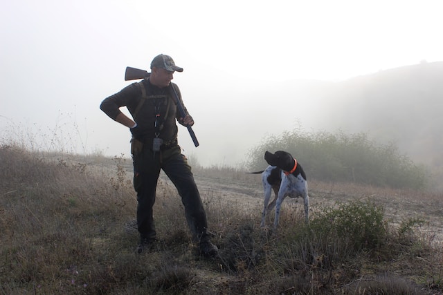 hunter holding gun with dog and best hunt gear in a foggy field